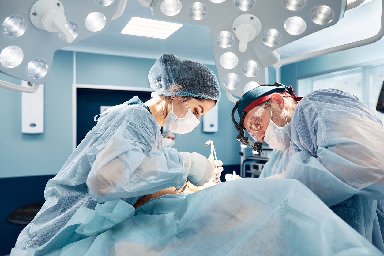 The image shows two surgeons operating on a patient and represents the most common types of reconstructive surgery.