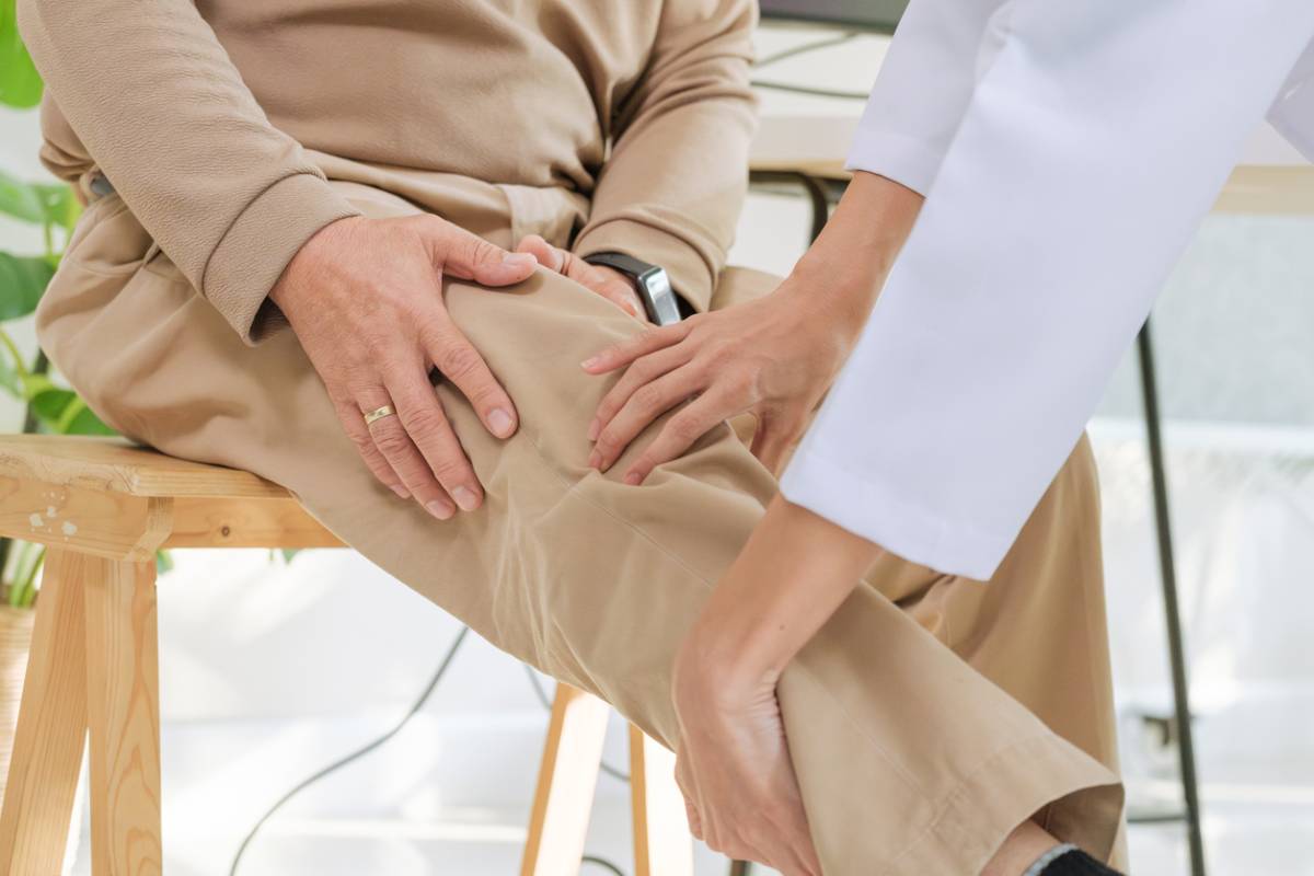 Doctor examining senior patient for osteoarthritis and knee pain.