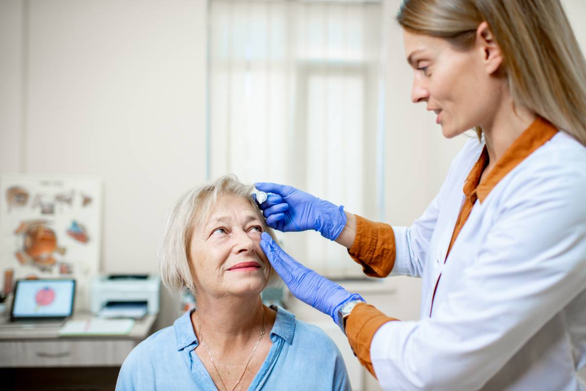Female doctor examining eyes of a senior patient.
