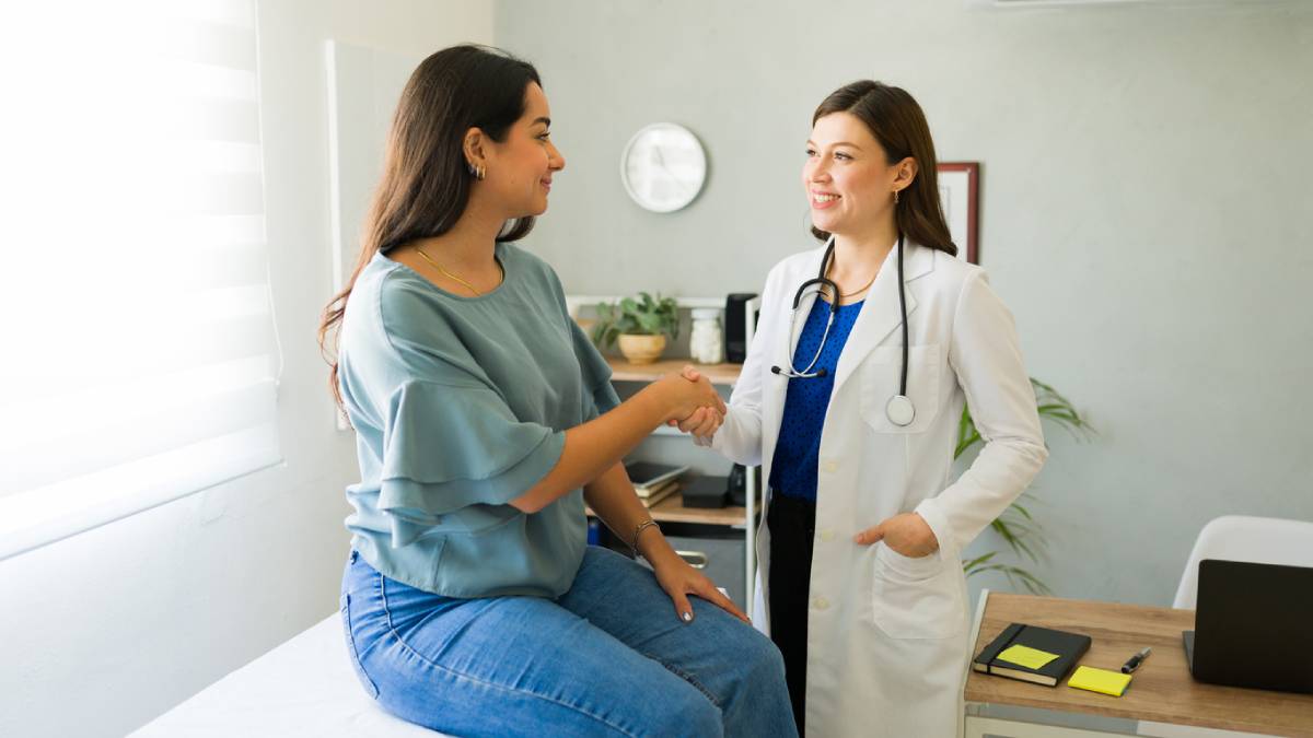 Female doctor smiling and shaking hands with her patient after a consultation in her office.